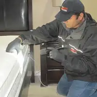 Bed bug inspection technician checking a mattress and bed frame for signs of infestation in Bloomington, IN