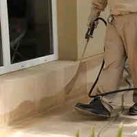 General pest control technician spraying exterior perimeter around a home in Bloomington, IN