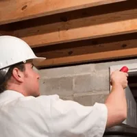 Termite inspection technician checking a basement wall and framing for termite activity in Bloomington, IN
