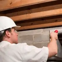 Termite inspection technician checking a basement wall and framing for termite activity in Bloomington, IN